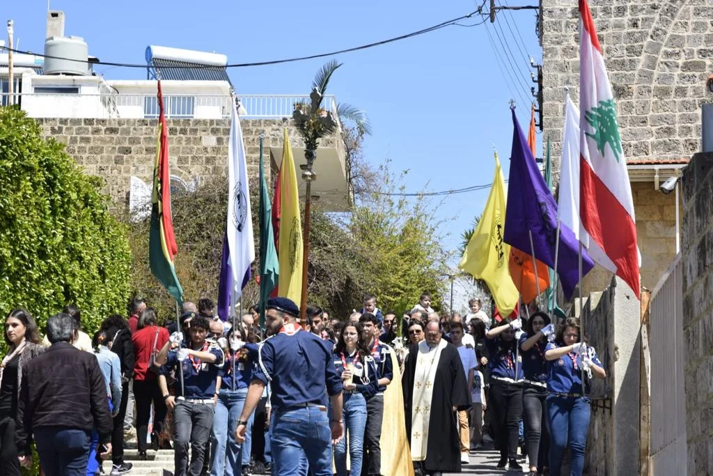 Scouts and parishioners with banners in a procession in Byblos