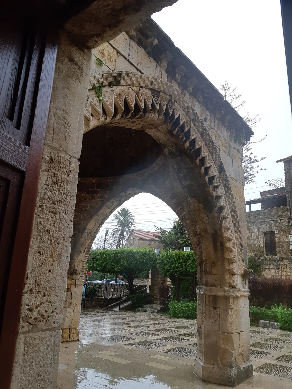Looking out through the carved arches of the baptistery onto the paved courtyard
