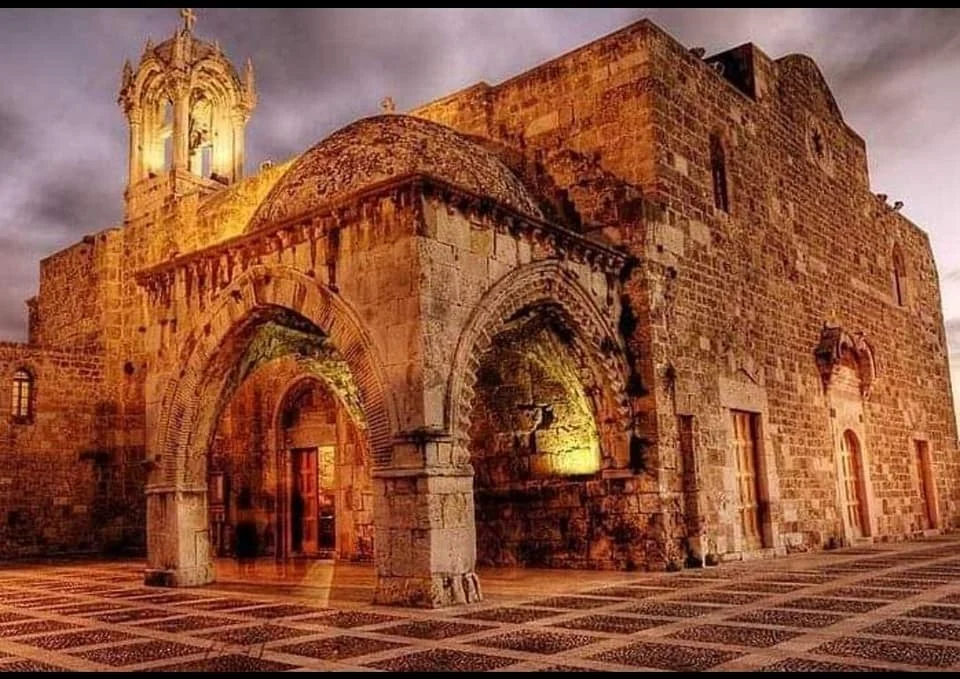 The stone porch and bell tower of Saint John Mark, lit at dusk