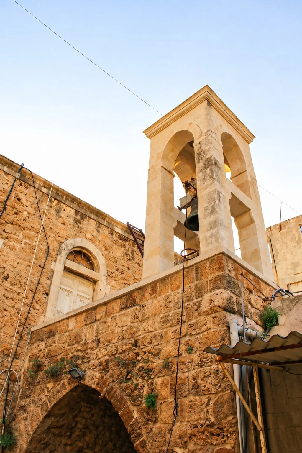 The stone bell tower of the shrine of Saint Aquilina above an arched doorway