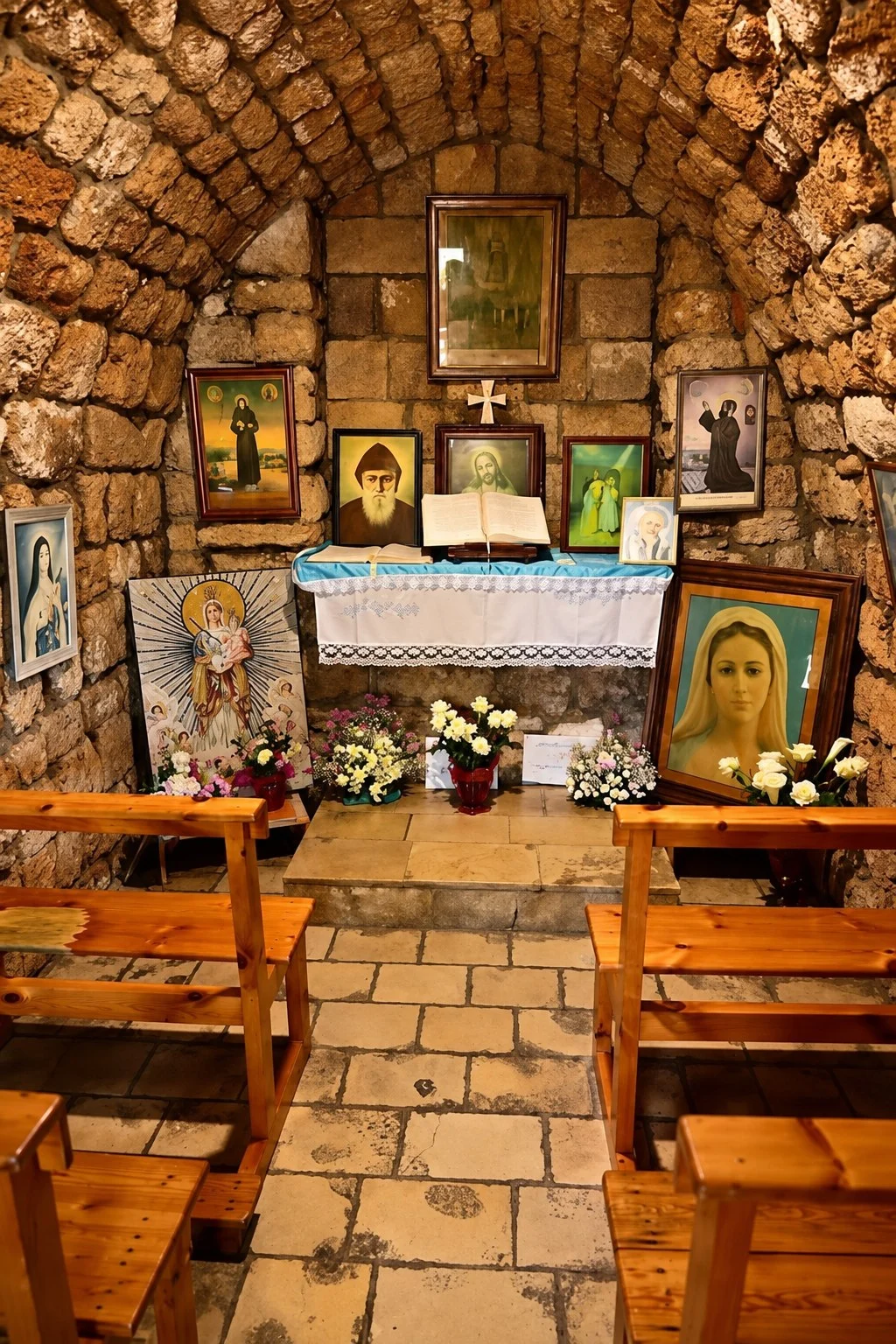 Inside Our Lady of Poverty: the old stone vault, wooden benches and a small altar hung with icons